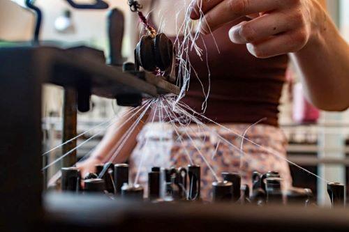 Mains tressant des fibres colorées, geste artisanal au cœur de l'atelier mercerie