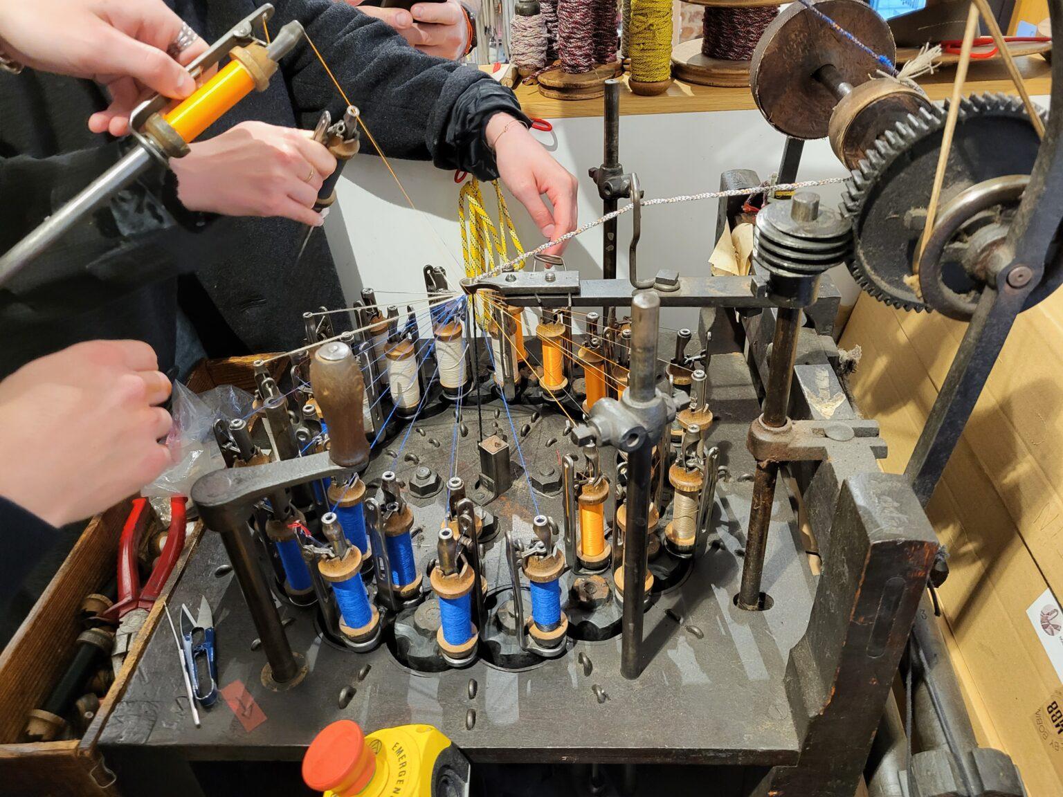 Historical industrial braiding machine with leather belts and wooden gears in a traditional Parisian textile atelier. on Wood Looms