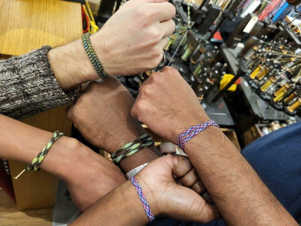 Close-up of colorful upcycled threads on vintage wooden spindles during a braiding machinery workshop.